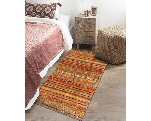 Scene met bed, nachtkastje en veelkleurig vloerkleed in etnische stijl