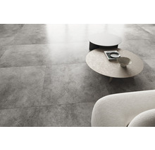 Lichte woonkamer met betonlook vloertegels, bank en salontafels