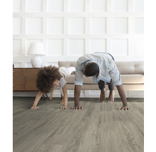 Vader en kind doen yoga op een grijze houten vloer in een lichte kamer.