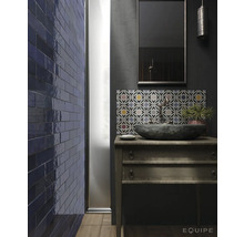Badkamer met stenen wastafel op houten commode, blauwe tegels op de muur en tegels met patroon boven het dressoir