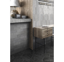 Interieur shot met grijze, rechthoekige wandtegels, plank en houten details.