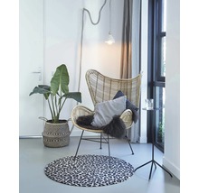 Lichte kamer scène met rotan stoel, decoratief tapijt, potplant en bijzettafel