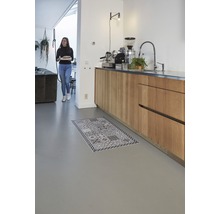 Lichte kamer met kitchenette en een vrouw met een bord en een tapijt op de vloer.