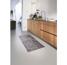 Interieurscène met keukenblok met houten fronten, keukenkraan, koffiemachine en een vloerkleed met motief op de vloer