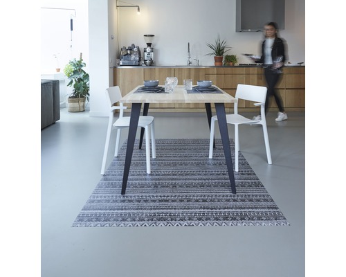 Eetkamer met houten tafel, witte stoelen en een tapijt met motief
