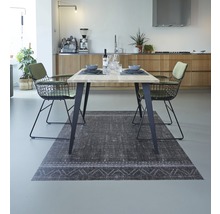 Eetkamer met tafel, stoelen en vloerkleed in een lichte ruimte.