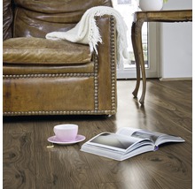 Woonkamer met laminaatvloer in houtlook, fauteuil, tafel en boek