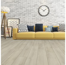 Woonkamer met lichte houten vloer, gele bank en decoratieve elementen zoals een klok en een staande lamp