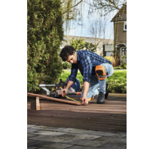 Een man meet een houten plank met een meetlint voor een afkortzaag in de buitenlucht.