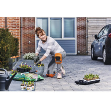 Vrouw plant bloemen in potten in de tuin met kniebeschermers