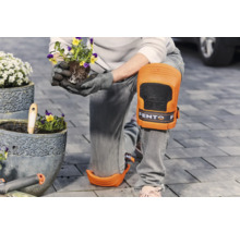 Persoon met kniebeschermers plant bloemen in een pot