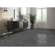 Woonkamer met donkere vloertegels, dressoir, staande lamp en kamerplant