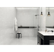 Lichte badkamer met mozaïektegels op de muren, douche en wastafel.