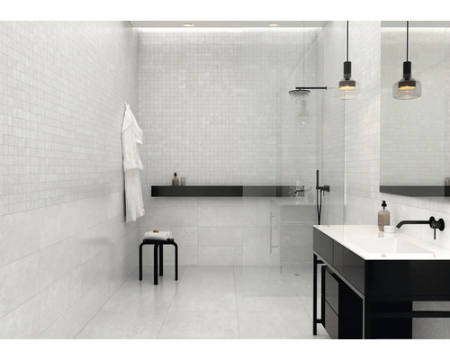 Lichte badkamer met mozaïektegels op de muren, douche en wastafel.