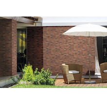 Terras met bakstenen muur, parasol en rotan stoelen.