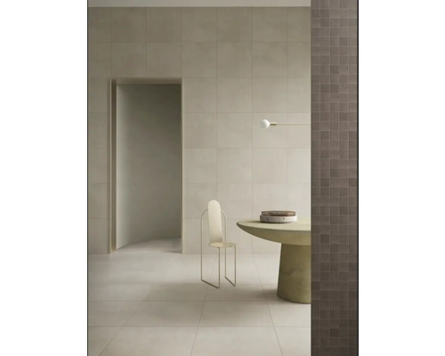 Lichte ruimte met tegels op de wand en vloer, minimalistische stoel en ronde tafel