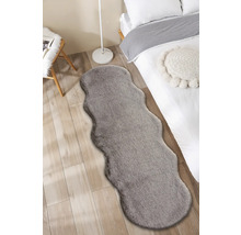Interieurfoto van een slaapkamer met een bed en een grijs tapijt in een harig design.