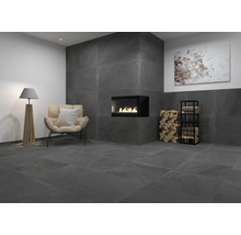 Woonkamer met antracietkleurige tegels, open haard, fauteuil en staande lamp