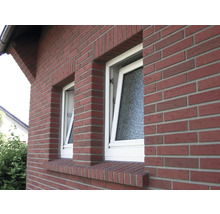 Buitenkant van een bakstenen huis met twee ramen