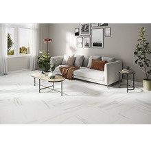 Lichte woonkamer met witte bank, salontafel en witte vloer met marmerlook.
