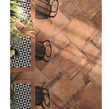 Vloer met terracotta tegels, tafels en stoelen.