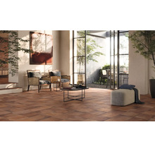 Lichte woonkamer met terracotta tegels, fauteuils en uitzicht op de tuin