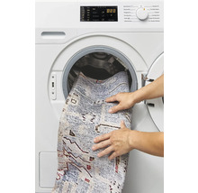 Een persoon plaatst een tapijt in een wasmachine.