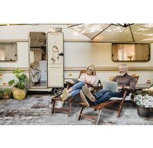 Een stel ontspant voor een caravan met laptops en een vloerkleed