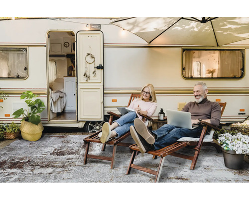 Een stel ontspant voor een caravan met laptops en een vloerkleed
