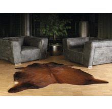 Woonkamer met twee grijze leren fauteuils en een bruin koeienhuidtapijt