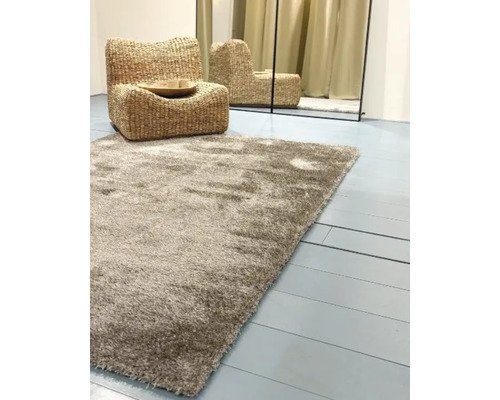 Hoogpolig tapijt met fauteuil van waterhyacint en spiegel op de achtergrond