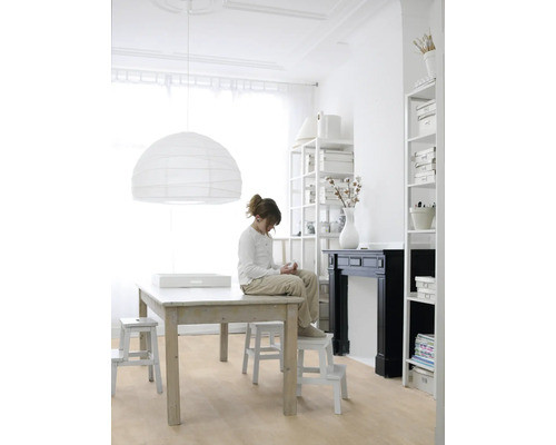 Lichte kamer met houten vloer, grote tafel, papieren lamp en een kind dat op een kruk zit