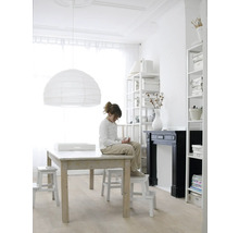 Lichte ruimte met tafel, stoelen, boekenkasten en een meisje dat op een kruk zit