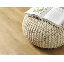 Decoratieve gebreide poef met open boek op houten vloer