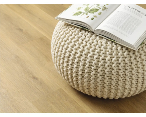 Decoratieve gebreide poef met open boek op houten vloer