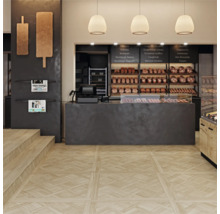 Moderne bakkerij met lichte vloertegels in houtlook met decoratief parketpatroon en een donkere verkoopbalie.