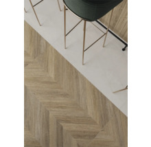 Keramische vloertegels in houtlook met chevronpatroon naast lichte tegels, moderne barkruk.