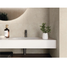 Moderne badkamer met lichte wandtegels in steenlook, wit wastafelmeubel met zwarte kraan en verlichte ronde spiegel.