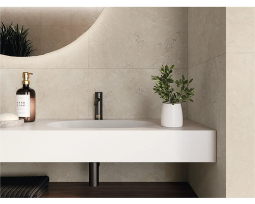 Moderne badkamer met lichte wandtegels in steenlook, wit wastafelmeubel met zwarte kraan en verlichte ronde spiegel.