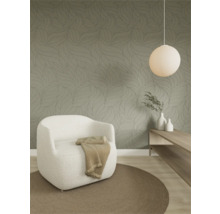 Moderne woonkamer met behang met bladpatroon, een fauteuil van gestructureerde stof, een rond tapijt en een houten plank.