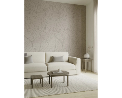 Lichte woonkamer met behang met bladmotieven in neutrale tinten, een crèmekleurige bank en moderne houten tafels.