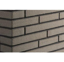 Close-up van een muur met smalle, gestructureerde steenstrips en diepe horizontale voegen.