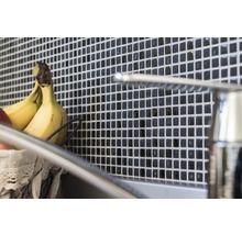 Wandtegels met mozaïekpatroon achter een gootsteen met kraan en fruitmand