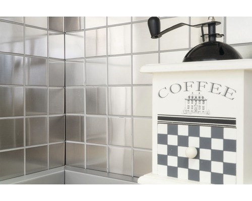 Vierkante metalen tegels aan de wand met een decoratieve koffiemolen