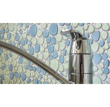 Close-up van een waterkraan voor een wand met mozaïektegels in kiezelpatroon