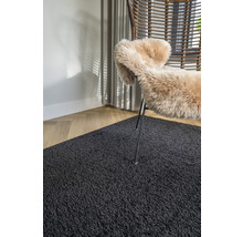 Interieurvoorbeeld met een zwart tapijt, een fauteuil en een schapenvacht
