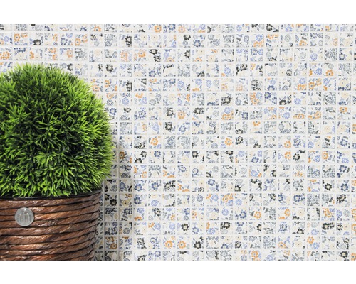 Decoratieve mozaïektegel met bloemmotief en kunstplant in pot.