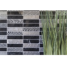 Decoratieve mozaïektegels in zwart, wit en grijs naast siergras