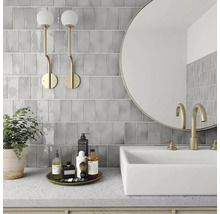 Moderne badkamer met grijze tegels, ronde spiegel, wastafel en gouden kranen