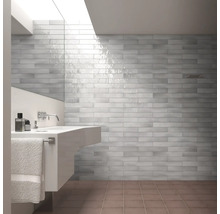 Lichte badkamer met grijze wandtegels in baksteenlook, wastafel en handdoek